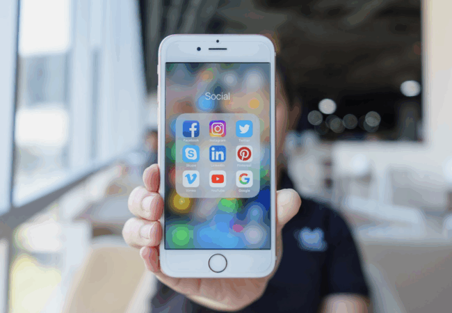 Someone holding a phone with social media icons on it